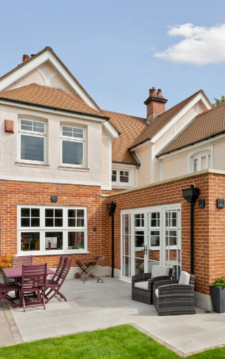 Substantial property in Hampshire with red brick and white fitted windows and patio doors.