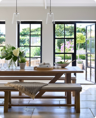 Beautiful dining room with oak dining table and bench with aluminium doors to garden.