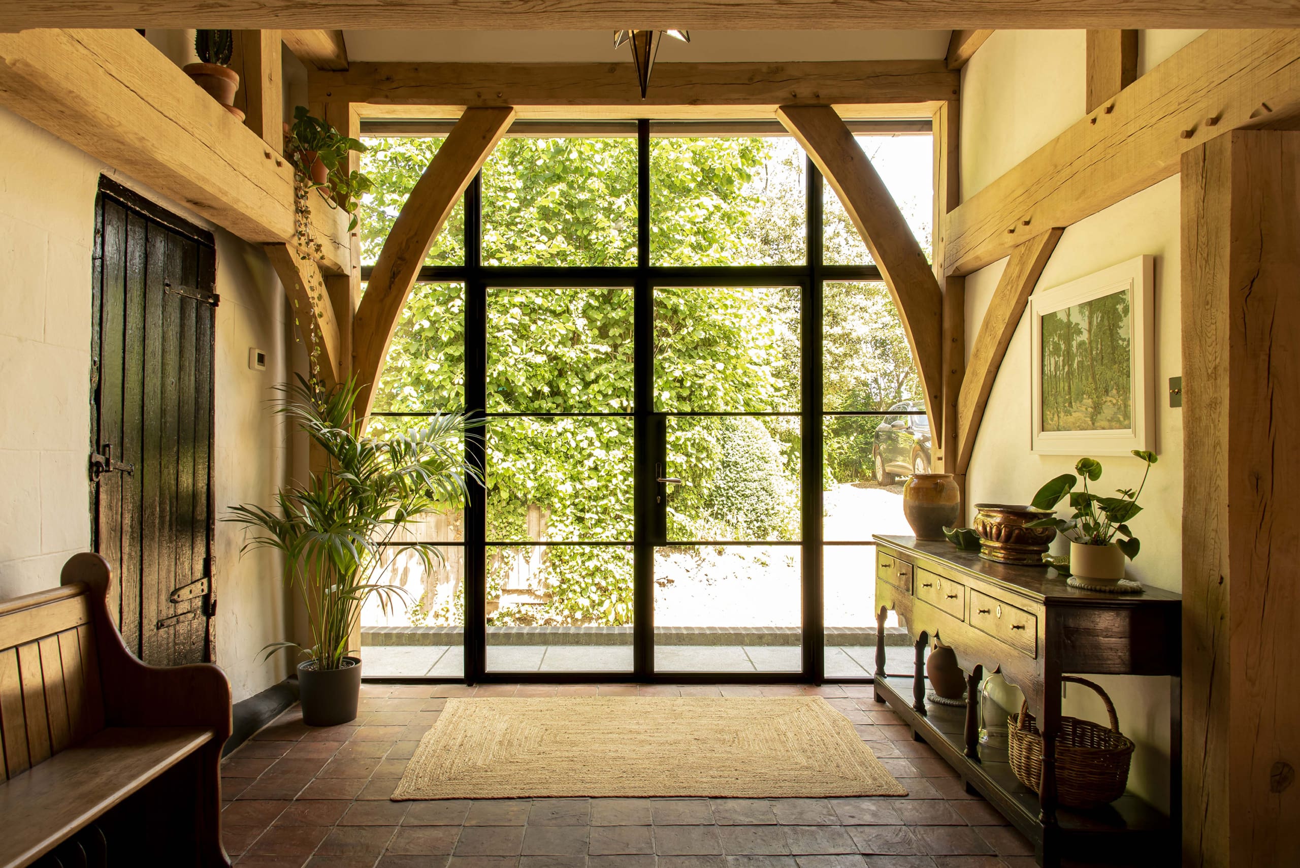 Hallway to substantial property with timber beams and aluminium door.