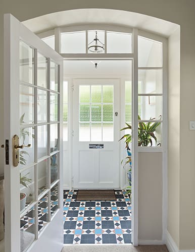 Traditional entrance porch with vintage floor tiles and wooden doors.