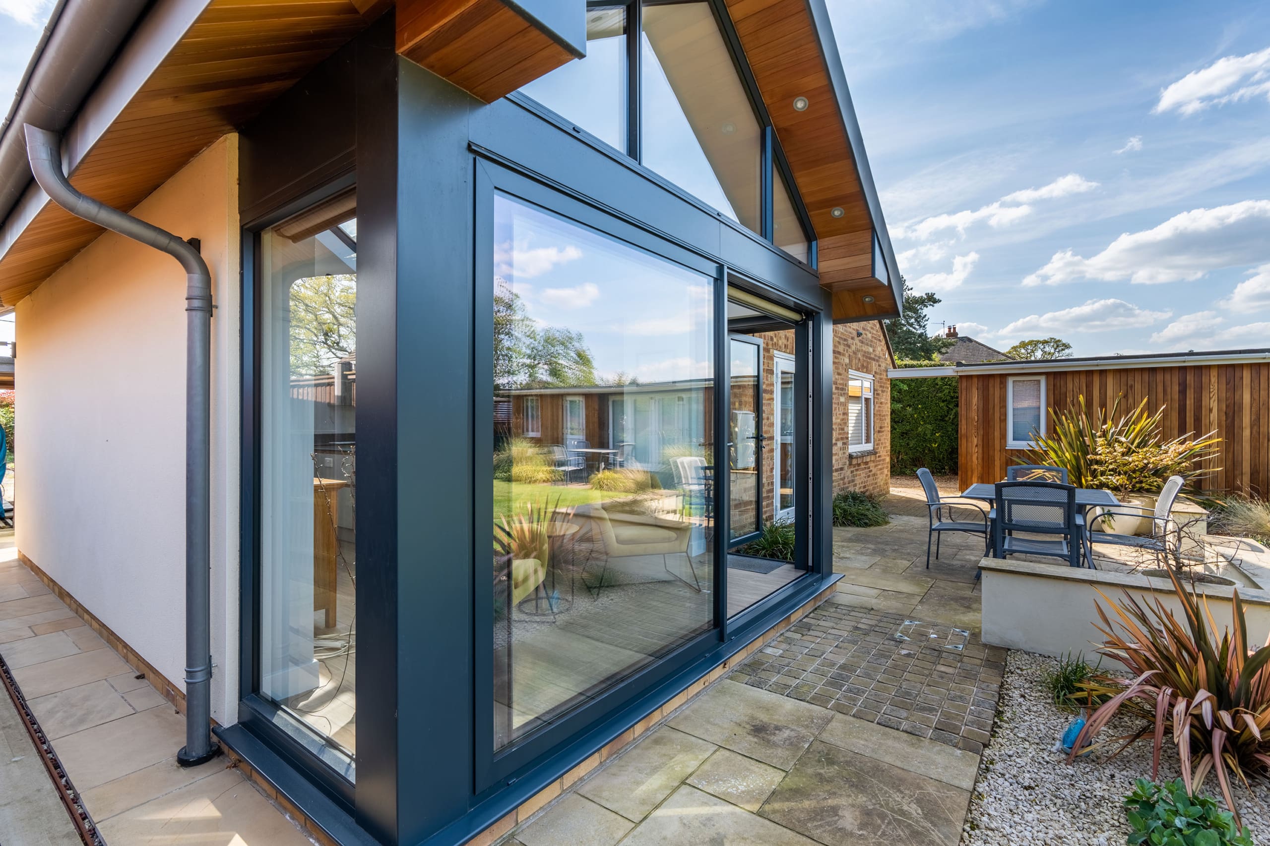 Zinc orangery extension with zinc roof and roof lantern and sliding doors to garden.
