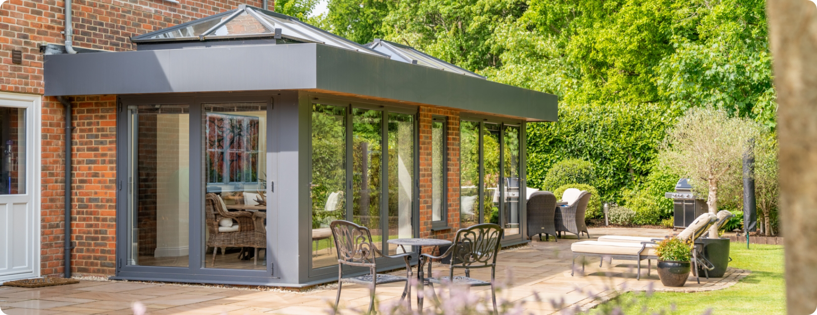 Stunning orangery with grey framework to the doors and windows and roof lanterns.
