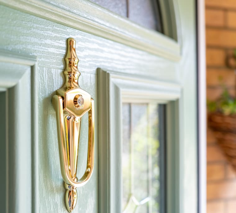Brass doorknocker mounted on a composite door in olive green.