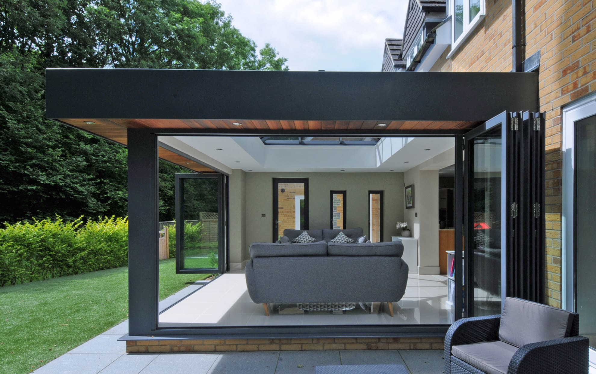 Contemporary living room interior with roof lantern and open bifolding doors.