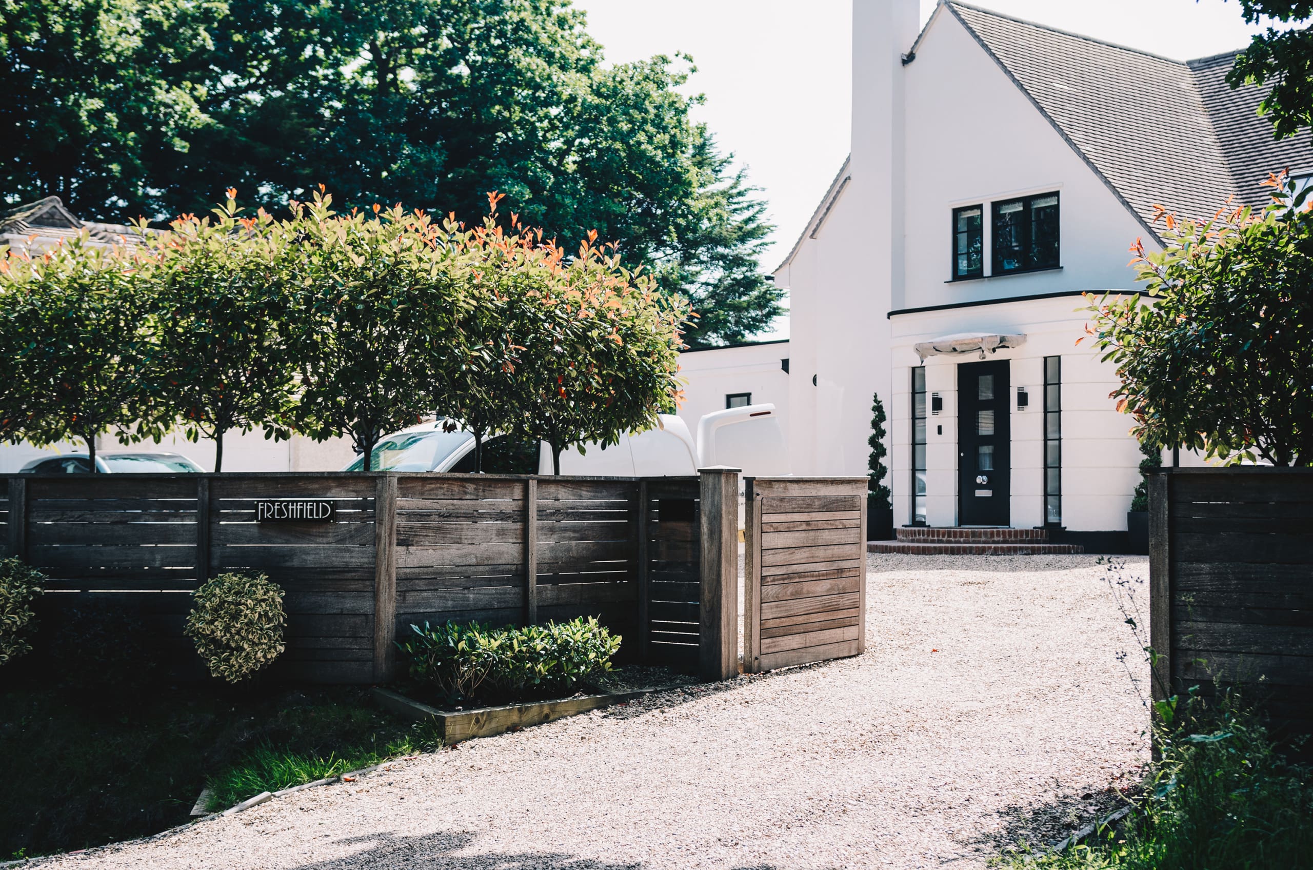 Art deco property in Lymington with gravel driveway and wooden gate.