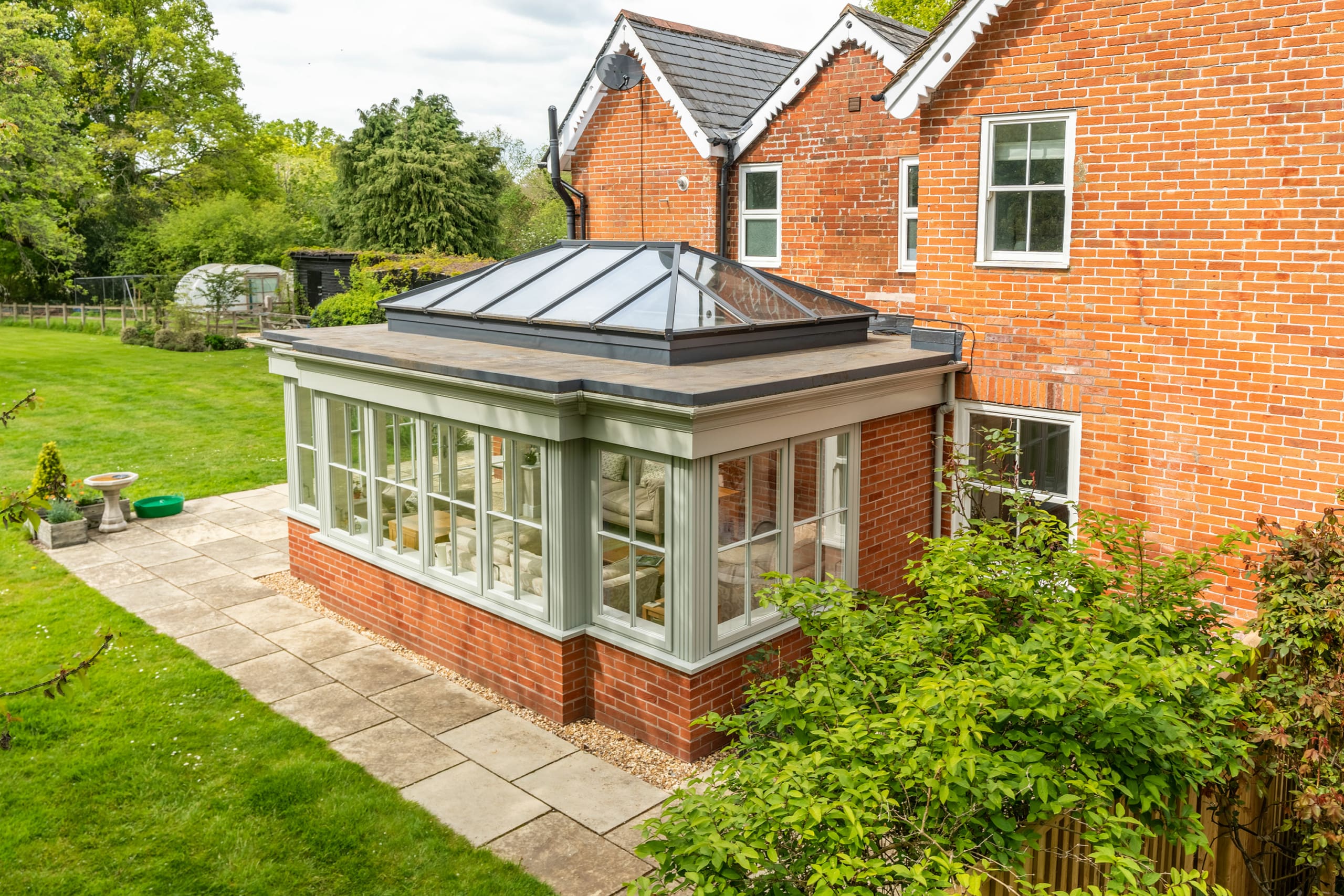 Orangery exterior with roof lantern and green framework.