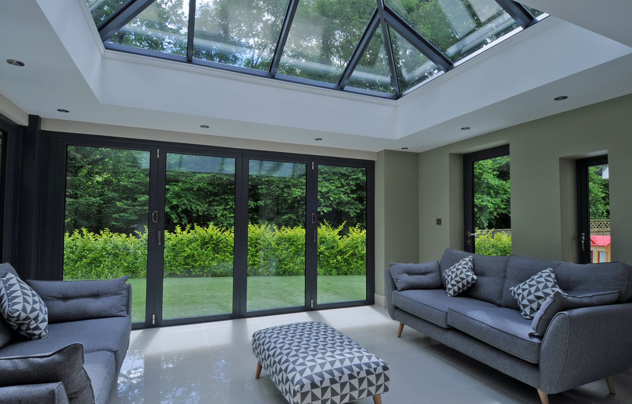Contemporary living room interior with roof lantern and bifolding doors.