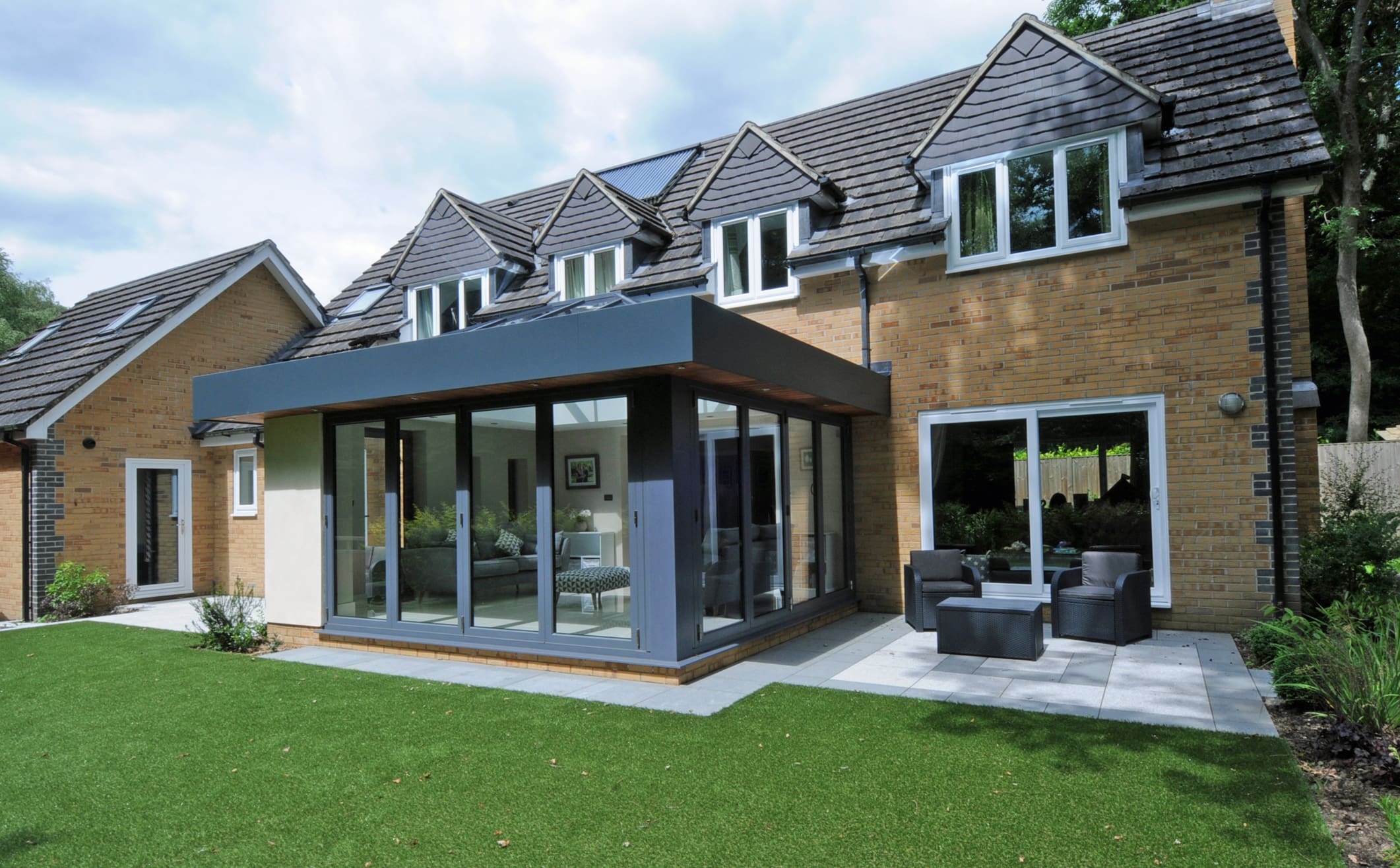Rear of a substantial property with orangery extension and bifolding doors.