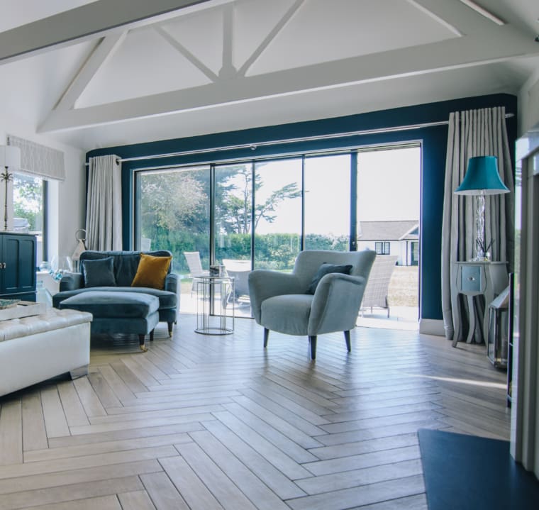 Modern living room with herringbone wooden floor and sliding glass doors.