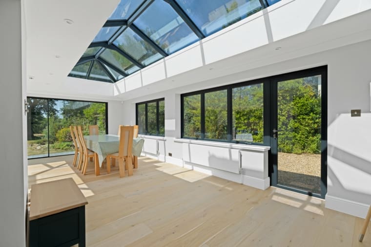 Beautiful modern extension with black aluminium glazing including sliding doors and roof lantern.
