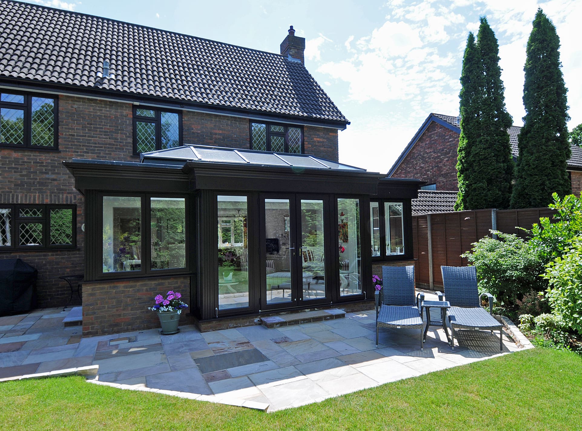 Exterior view of a kitchen extension featuring bespoke glazing with black frames.