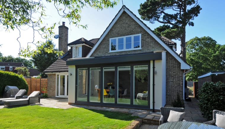 Rear elevation of a family home with rear view of the kitchen extension and bi-folding doors.