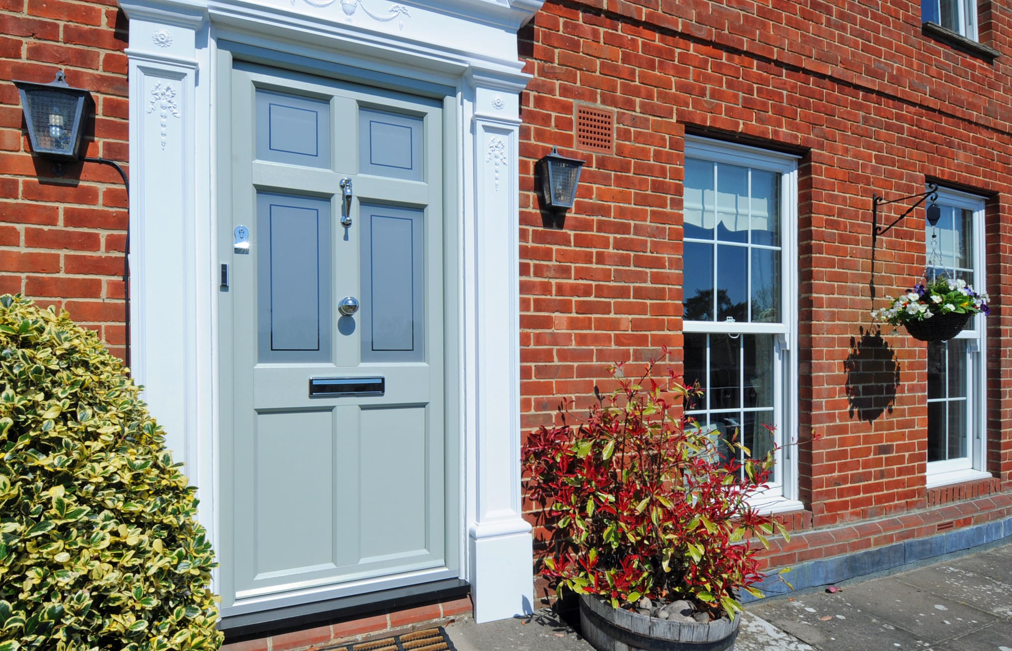 Traditional front door to townhouse property in olive green with silver furnishings.