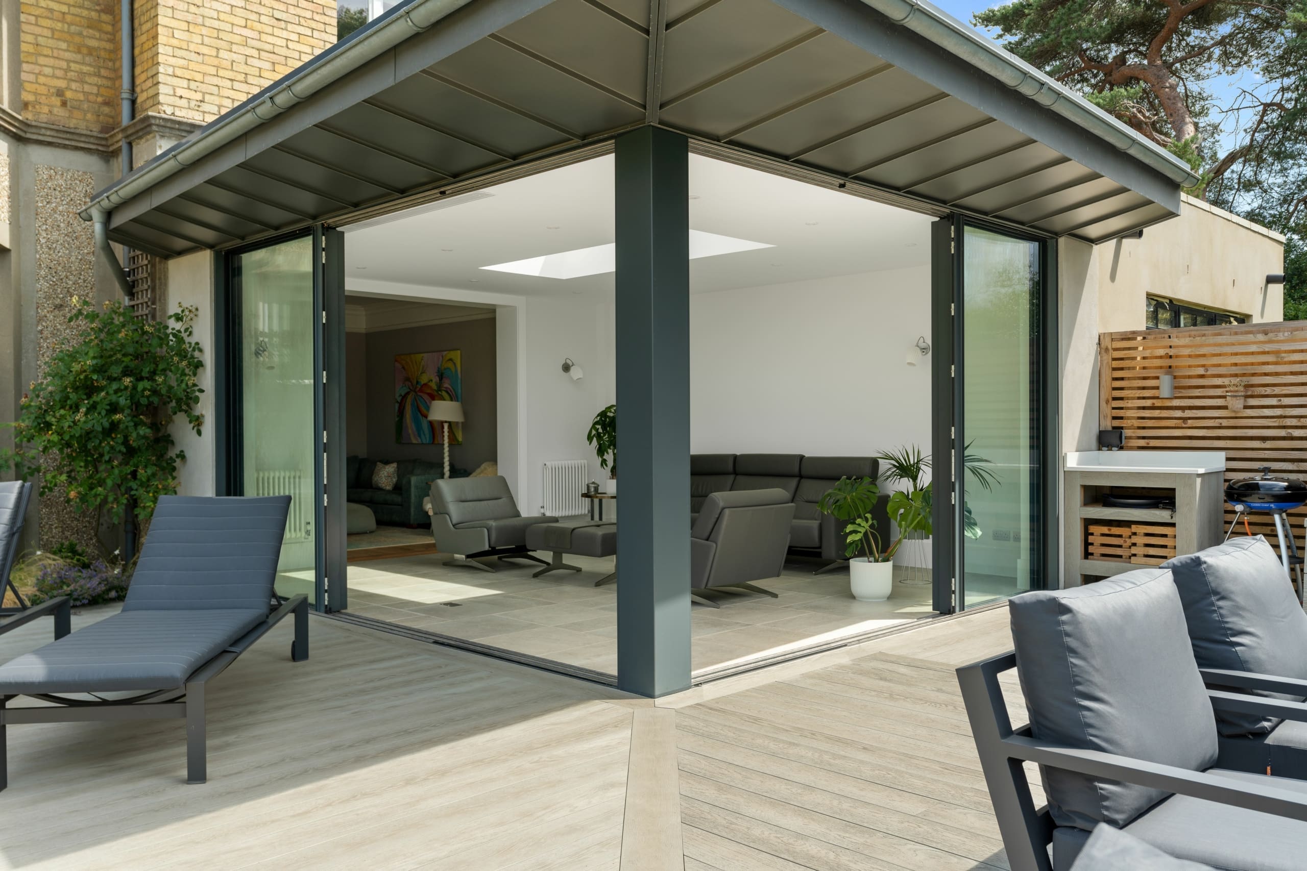 Beautiful sliding external aluminium doors leading to a garden with sun loungers on the decking.