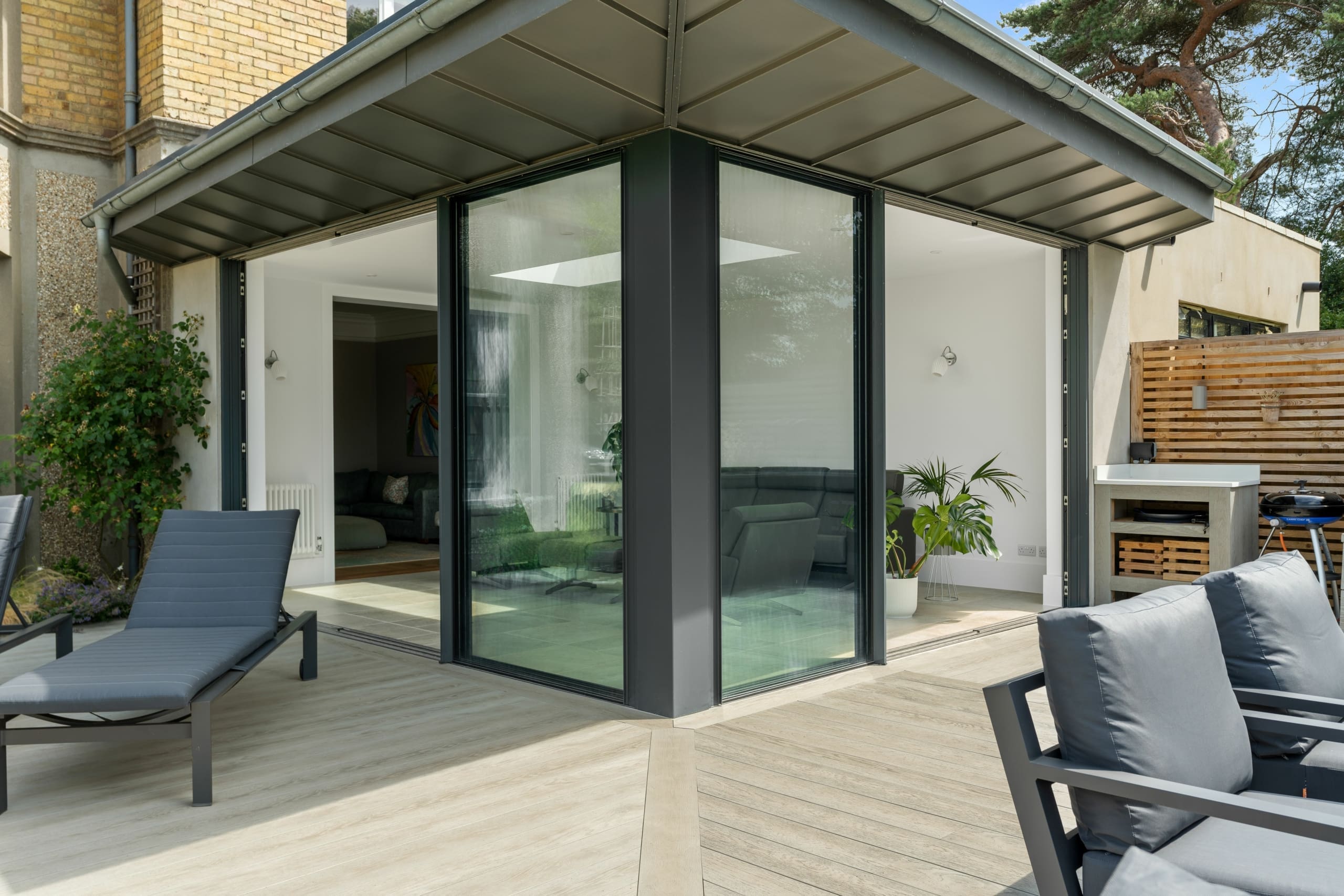 Beautiful sliding external aluminium doors leading to a garden with sun loungers on the decking.