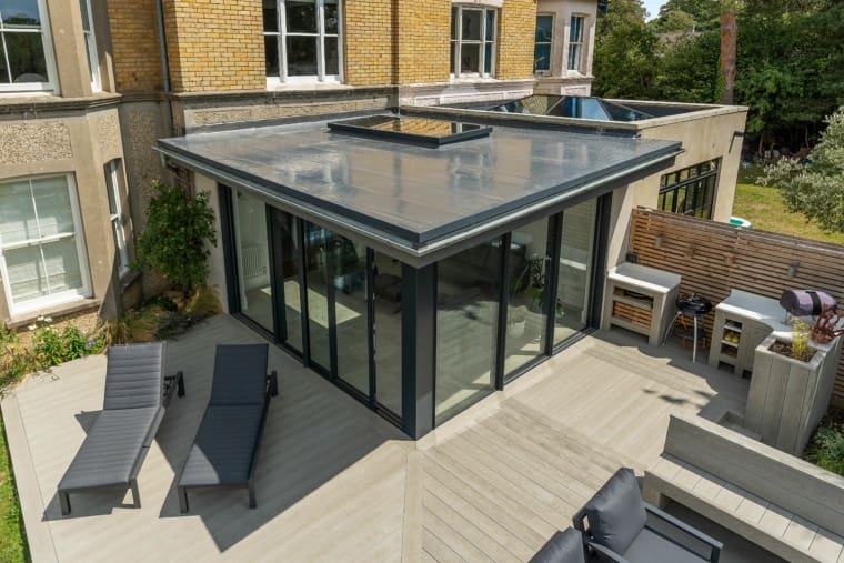 Orangery extension to a substantial townhouse featuring flat roof, roof lantern and aluminium doors and lightwood garden decking.