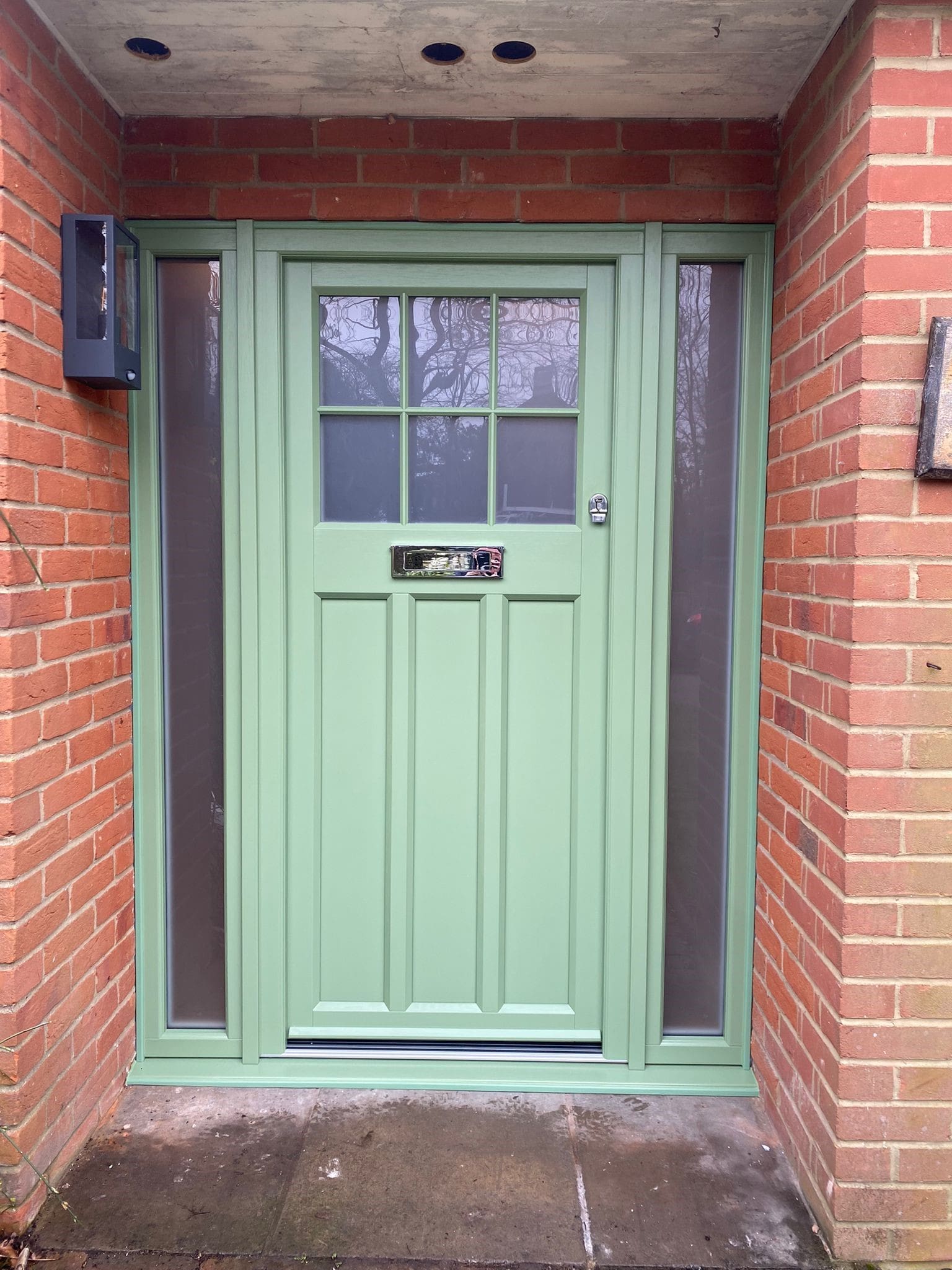 Front door finished in green with silver furnishings.