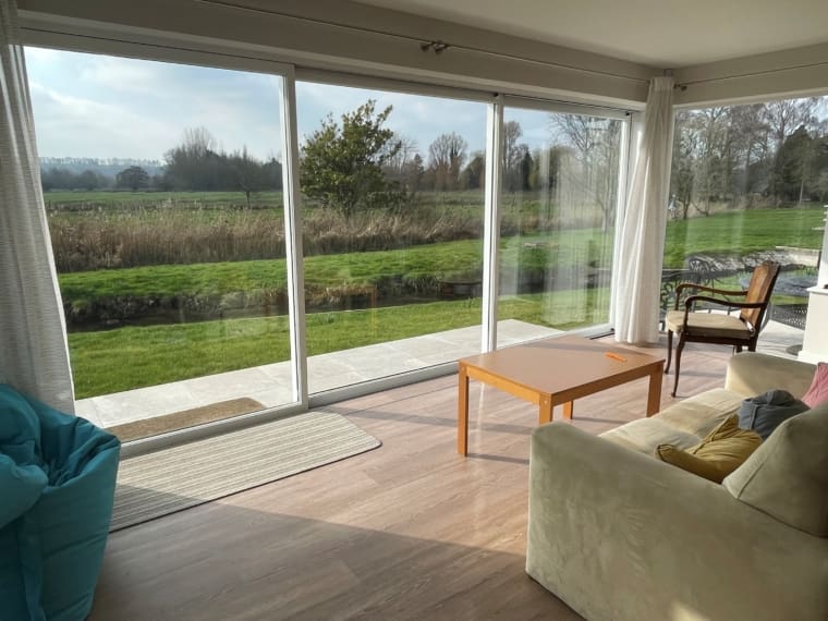 Living room with dual aspect sliding glass doors with a view to the fields.