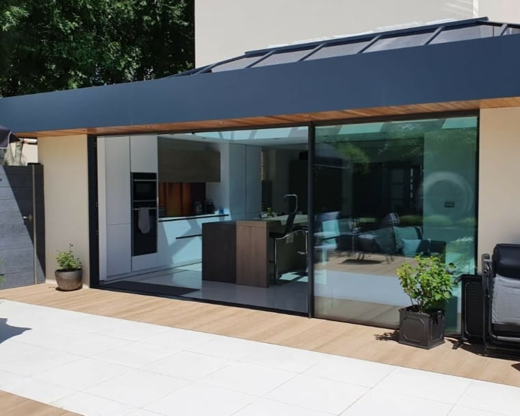 Stunning kitchen extension with glass roof and sliding glass doors to patio area.