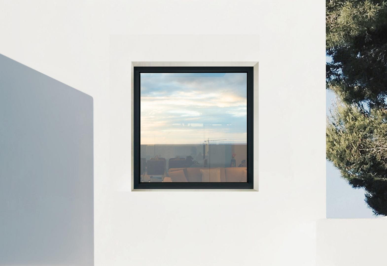 Window in a white wall with black frameowrk and a view overlooking a landscape.