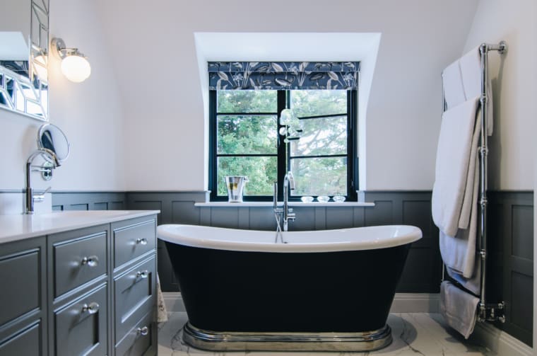 Stunning art deco style bathroom with floor elevated roll top bath tub and aluminium windows.