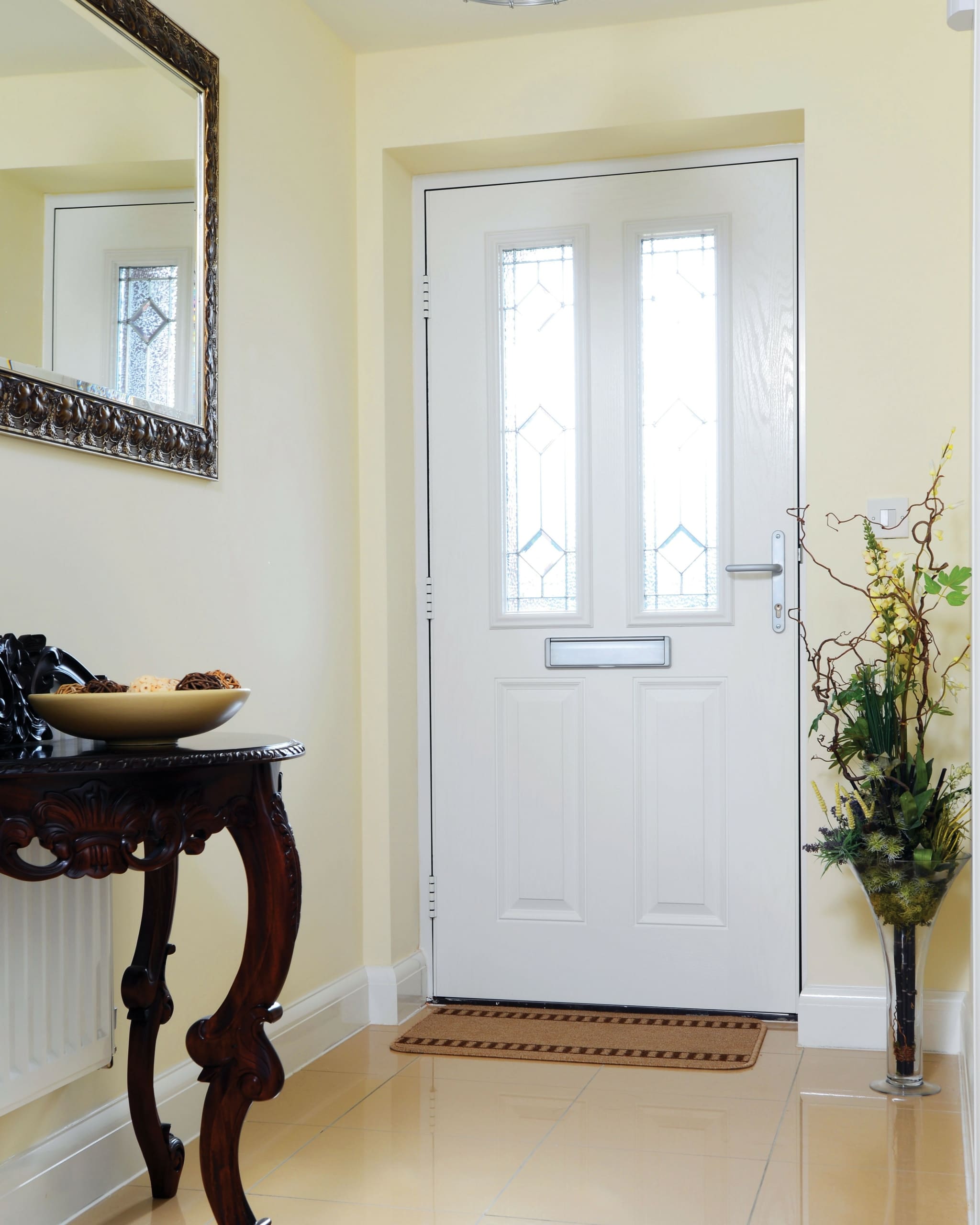 Hallway of a traditional home with a white front door and two windows with decorative design.
