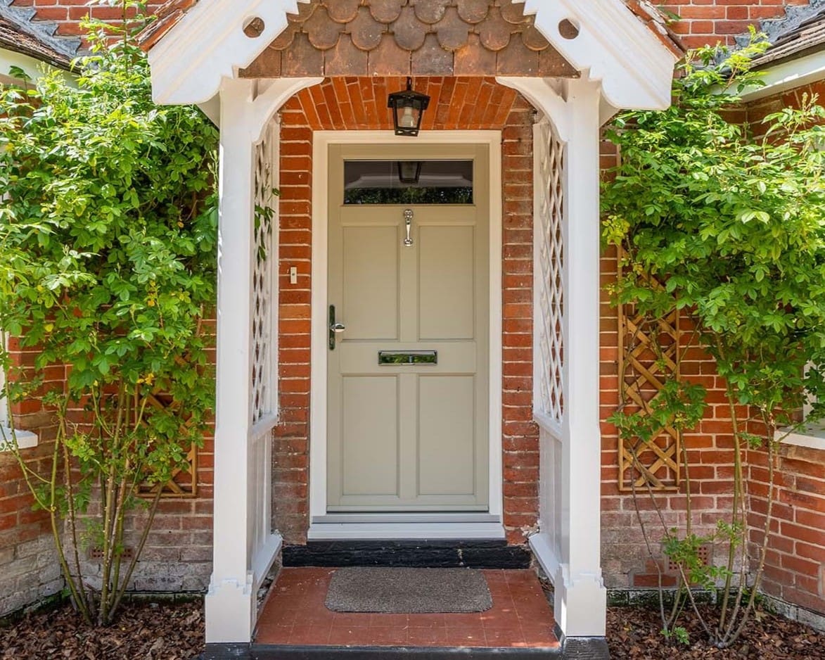Traditional front door finished in a light grey green colour with a painted white wooden porch surround.